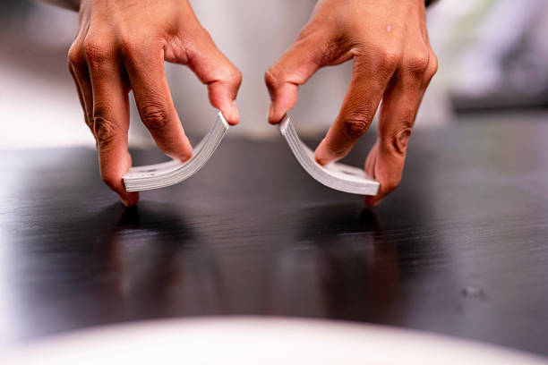 Two hands perform a swift card flourish on a dark wooden table, capturing dexterity and focus in a moment of street magic and intrigue.