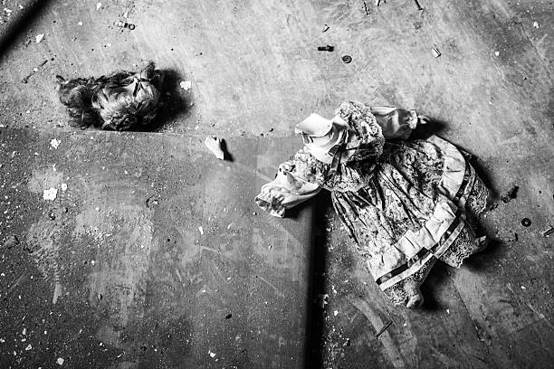 Photo of an old broken porcelain doll's head with empty eye sockets. It lies on a rusty metal base.