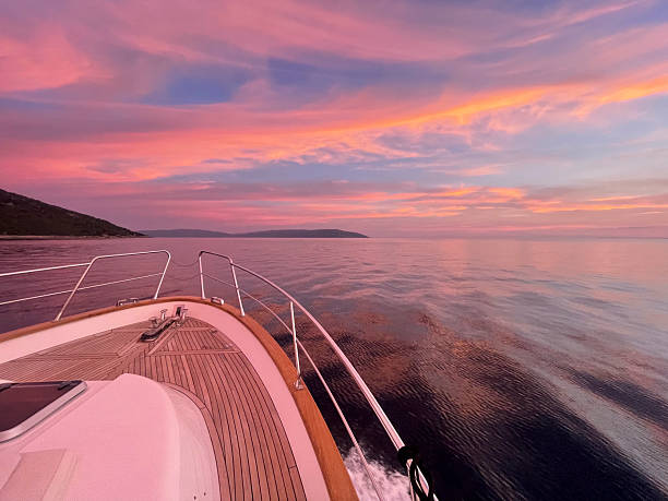 Navigating calm sea waters during golden hour with expansive coastal horizon and soft pastel sky reflecting on smooth water surface.