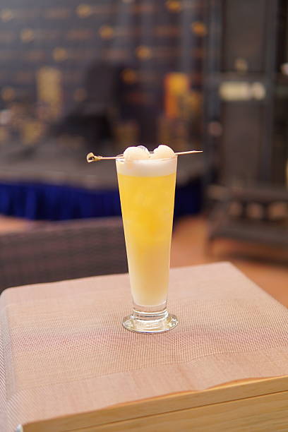 Vibrant yellow candle with two wicks sits in a clear glass holder on a textured surface, showcasing its artisanal quality