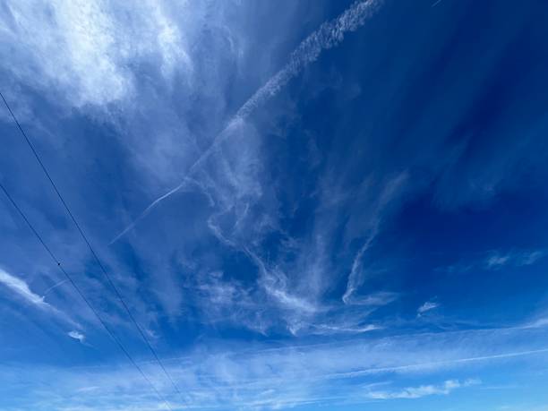 Wispy cirrus clouds and patchy altocumulus formations scatter across the sky, creating a layered texture above
