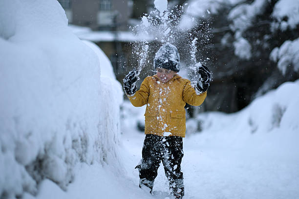 Little boy plays in snowing