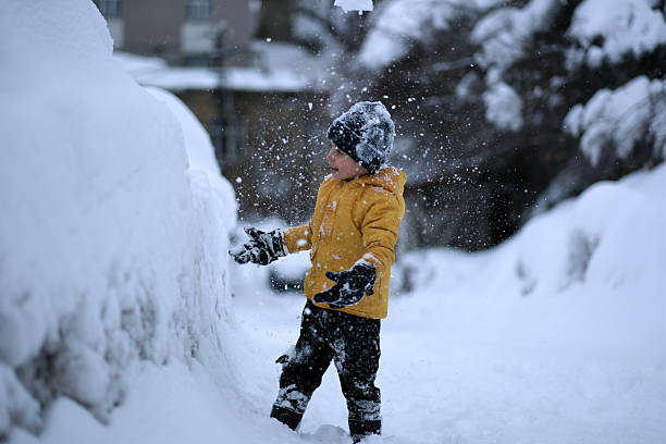 Little boy plays in snowing
