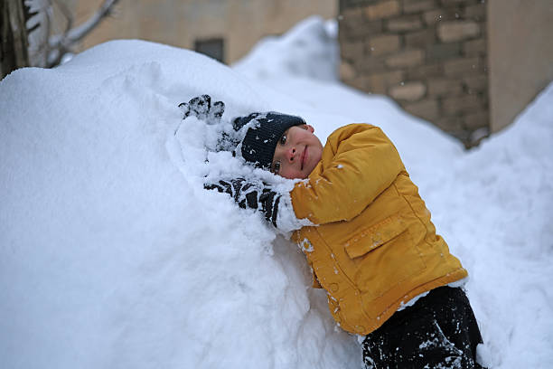 Child is playing in backyard garden of villa on winter day.