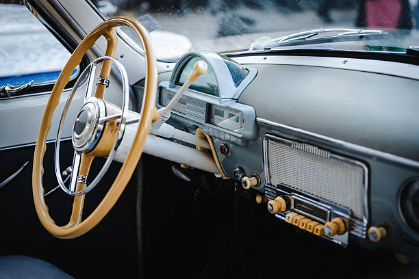 Close up of a vintage car interior featuring supple leather seats, a classic instrument panel with analog gauges, polished metal accents, and a retro steering wheel for automotive enthusiasts.