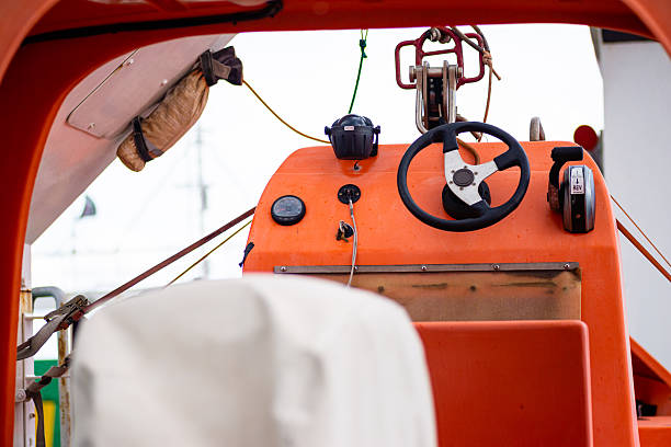 Detailed view of lifeboat cockpit with steering wheel and controls for maritime rescue operations.