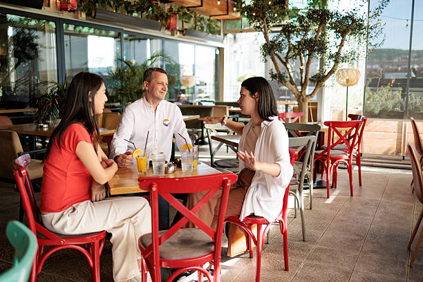 Three colleagues enjoying drinks and conversation at a modern restaurant during the day