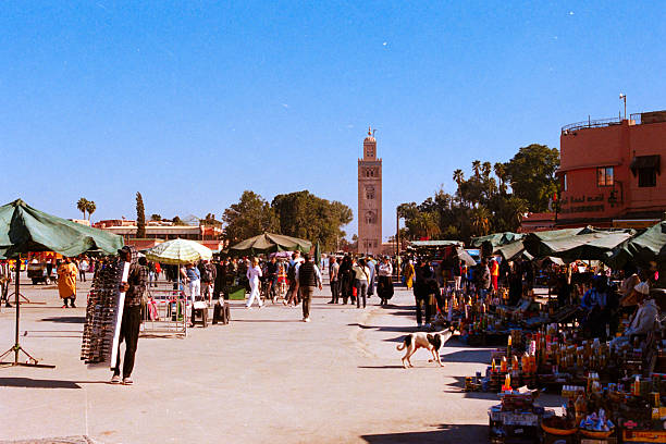 Marrakech, Morocco - November 26, 2025: Busy Jemaa el-Fnaa square in Marrakech showing a bustling Moroccan market with vendors, crowds, and the Koutoubia Mosque. Scanned from analog film