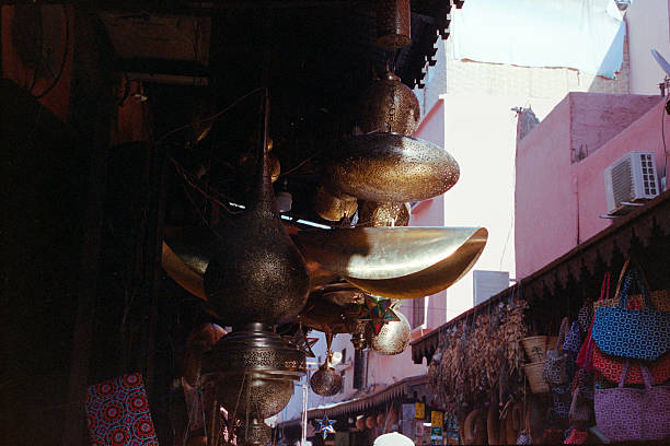 Metal lanterns and other artisanal items displayed in an outdoor market alleyway, evoking travel and culture. Scanned from analog film
