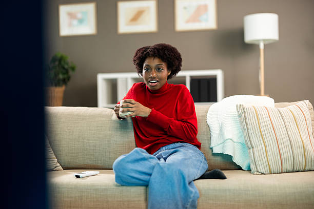 Young woman feeling surprised while relaxing on sofa with a hot drink