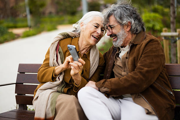 Happy mature couple enjoying digital content together on a smartphone outdoors