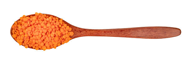 Lentil groats in a brown wooden spoon isolate on a white background.