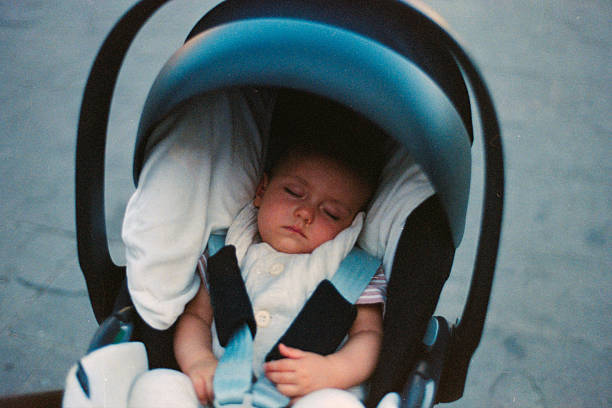 Newborn baby resting soundly in a secure car seat with safety straps, providing comfort and peace during travel. Scanned from analog film