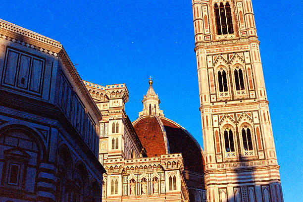 Florence Cathedral, its iconic dome and Giotto's Bell Tower standing tall under a clear blue sky, showcasing Italian architecture. Scanned from analog film