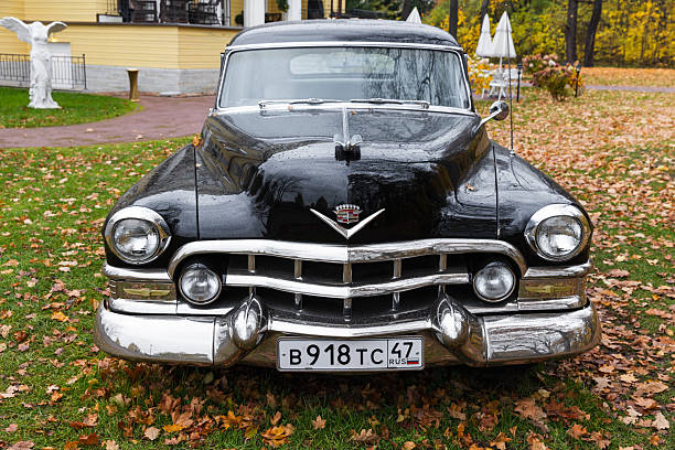 St-Petersburg, Russia - October 26, 2025: Shiny black Cadillac Fleetwood vintage car with chrome accents is parked on the lawn, front view. Perfect for vintage car, nostalgia, and lifestyle imagery