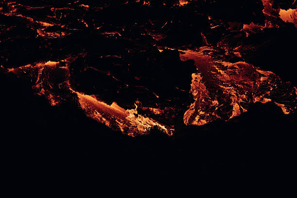 Molten lava streams illuminate the dark environment, featuring the intense heat and raw power of an active volcano eruption in the unique Icelandic landscape