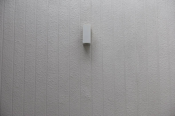 A wall with a light fixture on it. The light fixture is white and has a square shape. the metal lamp on wall.