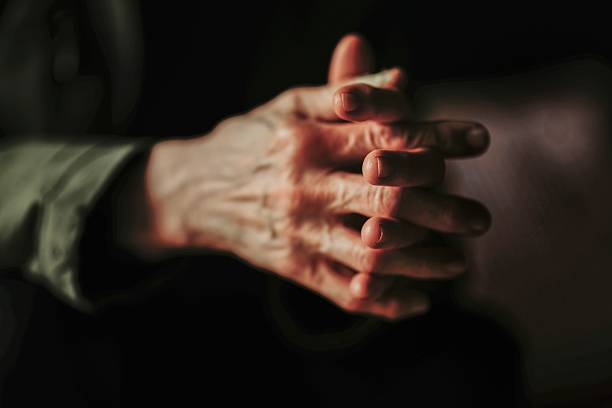 Closeup of the hands of a old caucasian woman with his hands clasped, in black and white photograph