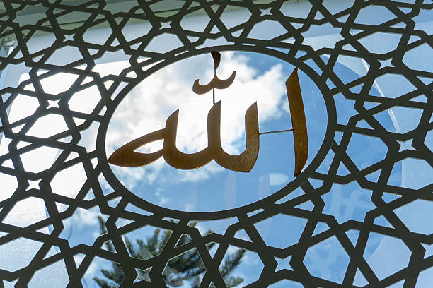 Golden Arabic calligraphy of the word 'Allah' placed on a decorative window with a sky background
