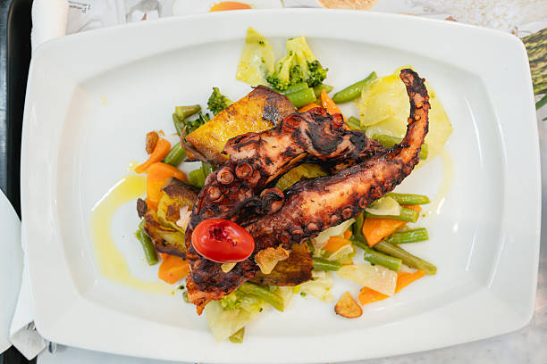 Overhead shot of a grilled octopus meal with colorful vegetables.