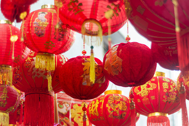 A vibrant stock image capturing traditional decorative Chinese lanterns hanging in a bustling Chinatown traditional market. The colorful lanterns showcase classic Asian craftsmanship and cultural heritage, creating a festive atmosphere often associated with Lunar New Year celebrations. This image is ideal for themes of Chinese culture, tradition, festivals, travel, and multicultural street markets in Asia.