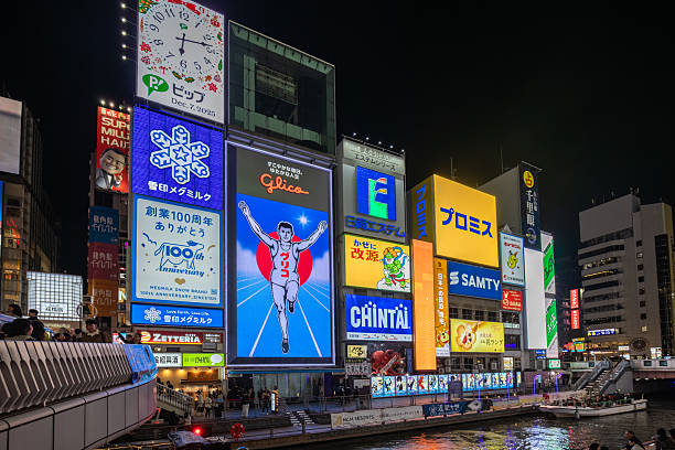 Kyoto, Japan - December 04, 2025: Vibrant night scene in Osaka's Dotonbori district, showcasing the iconic Glico Running Man sign amidst a dazzling array of neon billboards and urban energy.
