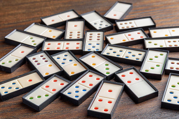 Playing dominoes at a wooden table for fun activity. White domino blocks. Board game for entertainment friends. Domino set.