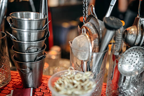 Tin cups and other accessories standing on bar counter at coffee shop