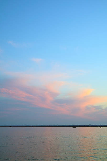 landscape with sea and blue sky at sunset with pink clouds