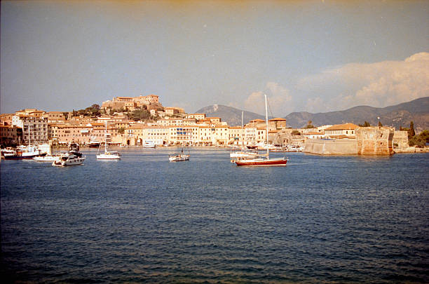 Capturing the historic Portoferraio town built along the beautiful harbor, with traditional buildings, boats, and a fortress. Scanned from analog film