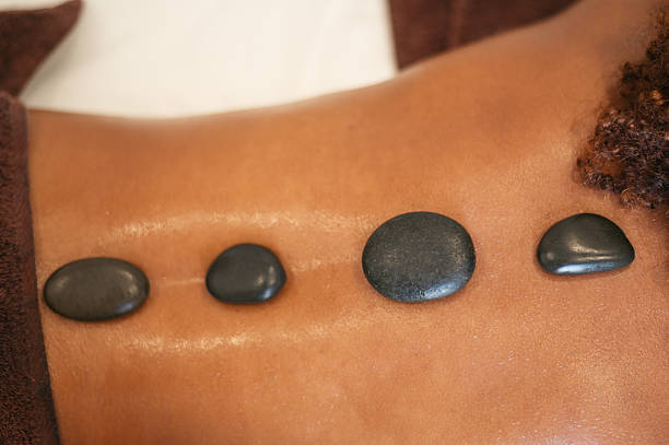 Person experiencing hot stone massage therapy on their back for relaxation and wellness