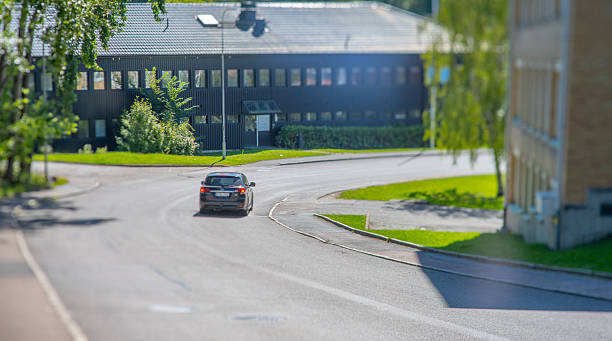 Car driving through quiet suburban street in sunlight