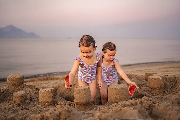 Young girls having fun playing creating sandcastles on the beach during summer vacation