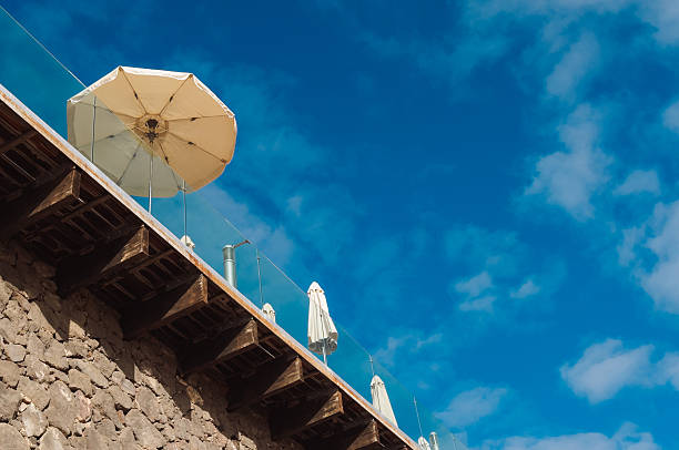 Yellow beach umbrellas seen from below against clear blue sky. Minimal summer travel background representing vacation, relaxation, leisure time and sunny holiday atmosphere with copy space.