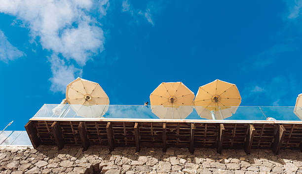 Yellow beach umbrellas seen from below against clear blue sky. Minimal summer travel background representing vacation, relaxation, leisure time and sunny holiday atmosphere with copy space.