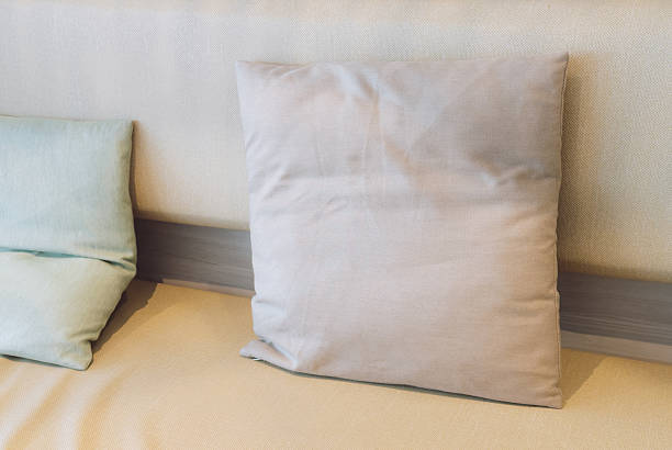 Decorative pillows arranged on sofa in cozy living room interior. Minimal home decor background with soft textures and neutral colors representing comfort, relaxation and modern lifestyle.