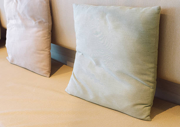 Decorative pillows arranged on sofa in cozy living room interior. Minimal home decor background with soft textures and neutral colors representing comfort, relaxation and modern lifestyle.
