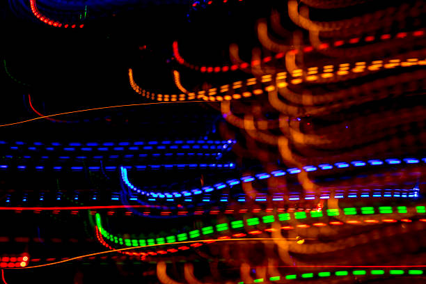 Bright light trails and spots create futuristic patterns against a dark backdrop. Abstract background with defocused lines and spots, made by glowing fiber optic lights.