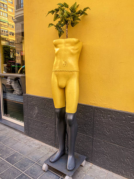 High angle close-up view of a yellow and black mannequin used as a planter for decoration purposes in the street.