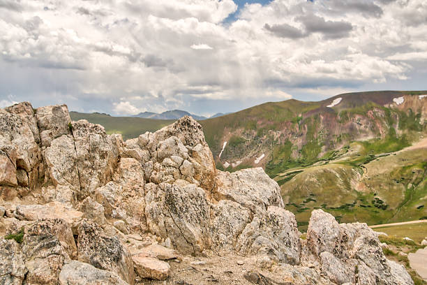 A rocky mountain top with a cloudy sky in the background. The sky is overcast and the mountain is covered in snow