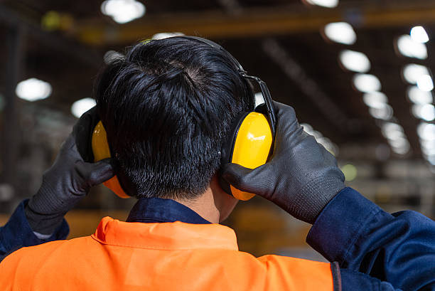 Close up asian man technician engineer wearing adjust protective safety helmet and safety headphone. Safety equipment for industry factory. Safety at work concept.