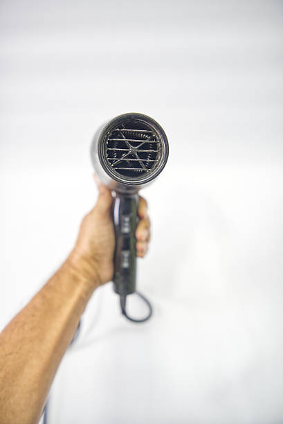 Close up photo of Senior Hairdresser blow drying client's hair in salon