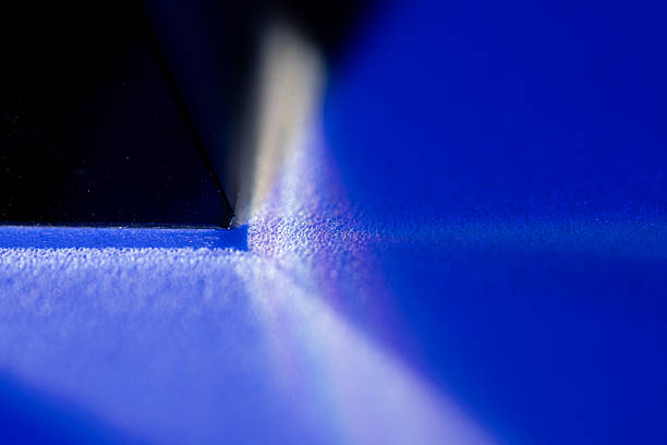 A detailed close up image capturing the tip of a translucent blue pyramid crystal against a deep blue background.