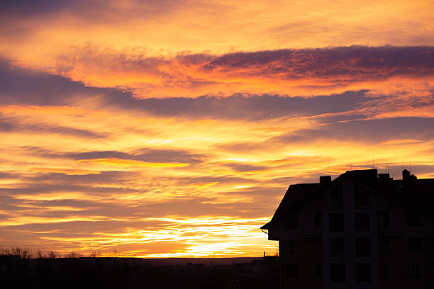 Vibrant sunset clouds painting the sky with warm colors above a dark building silhouette