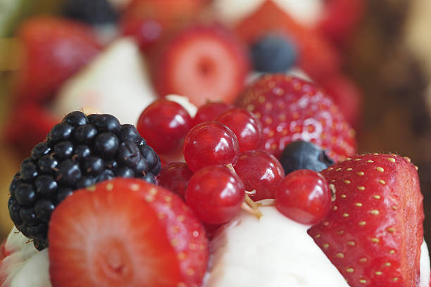 A slice of red velvet cake decorated with strawberries, pomegranate, and other fruits. Selective focus.