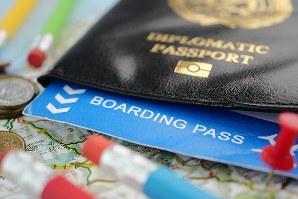 A diplomatic passport and boarding pass are on a map, ready to travel.
