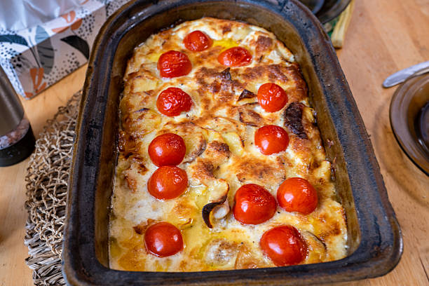 Gratinated creamy potatoes with cheese and potato in big baking dish on table.