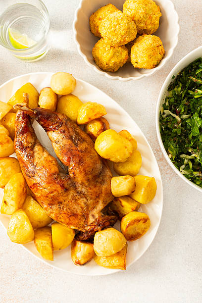 A hearty meal features a beautifully baked rabbit surrounded by golden potatoes, Accompanying the dish is a fresh salad, soft chickpea buns. This inviting setup showcases a warm dining