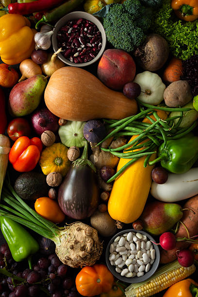 Fresh vegetables and fruits fill a surface after being gathered from the garden, showcasing a variety of colors and shapes during the harvest time in autumn