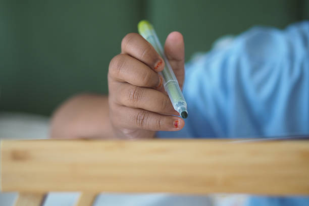 A young child draws attentively with a colored pen on a table.